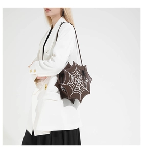 Detail view of brown spider web shaped crossbody bag with 3D spider charm for women