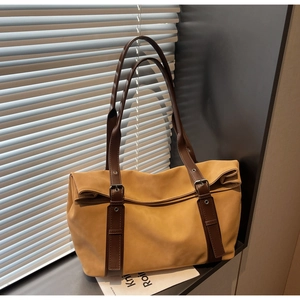 Detail of ginger yellow matte tote bag with dark brown handles and metal buckle