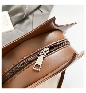 Detailed close-up of dark brown leather bag showing premium silver zipper and stitching