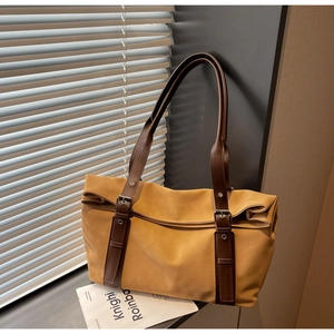 Detail view of ginger yellow tote bag with deep brown leather straps and buckle eyelets
