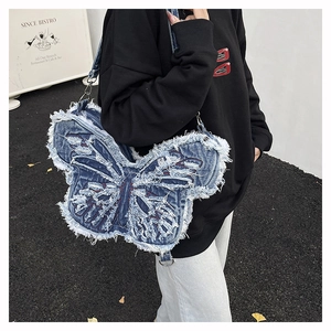 Close-up of butterfly denim shoulder bag with distressed edges and red embroidery detail