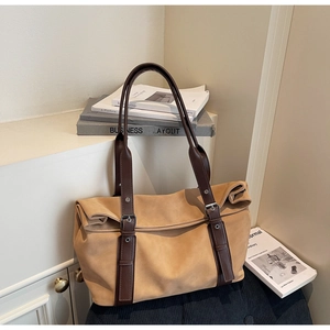 Close-up of khaki suede tote bag with brown leather straps and premium metal hardware