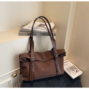 Detail of deep brown tote bag featuring leather straps and adjustable metal buckle