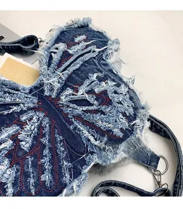 Detail of blue butterfly denim bag showing red stitching and distressed fringe texture