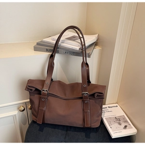 Detailed macro view of brown vintage tote bag with leather straps on a textured surface