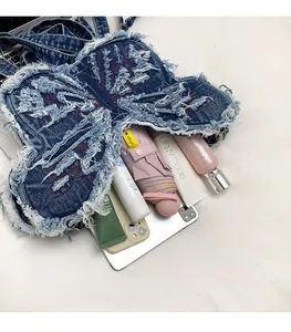 Macro view of butterfly denim bag showing spacious interior with daily essentials and embroidery