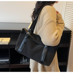 Detailed view of black nylon commute tote bag with leather strap on model's shoulder