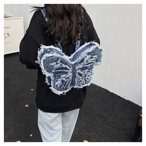 Detail of blue denim butterfly backpack featuring frayed edges and street style design