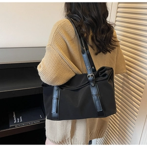 Detail of adjustable leather strap with metal buckles on a black nylon tote bag