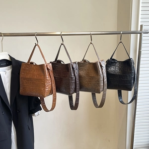 Four colors of mock crocodile leather bucket bags displayed on a minimalist fashion rack