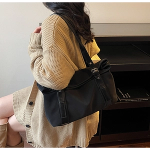 Detail of adjustable leather strap with metal buckle on black nylon commuter tote bag