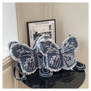 Detailed view of butterfly-shaped denim shoulder bag with frayed edges and washed finish