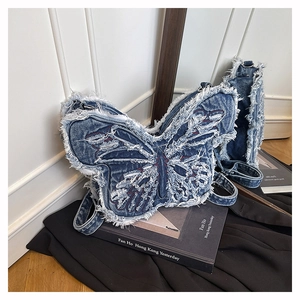 Detail of blue denim butterfly bag with white fringe edges and floral embroidery