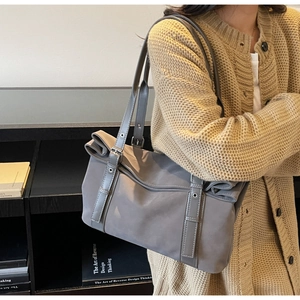 Grey nylon tote bag with decorative vertical straps worn over the shoulder by a model