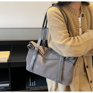 Close-up of grey commuter tote bag with adjustable leather straps and matte texture