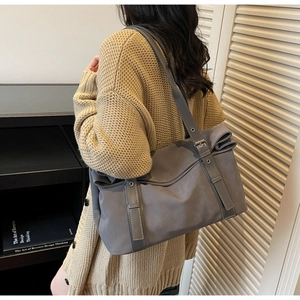 Detail of grey tote bag on shoulder showing metal buckle and minimalist nylon texture
