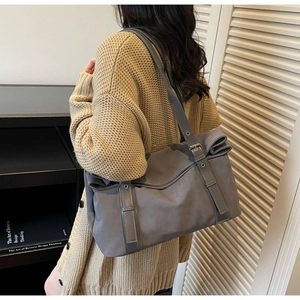 Detail view of grey tote bag with metallic buckle and eyelet accents on knitwear