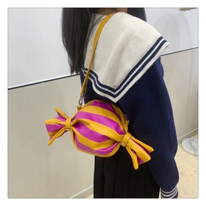 Detail view of a candy-shaped crossbody bag with pink and yellow stripes on a model