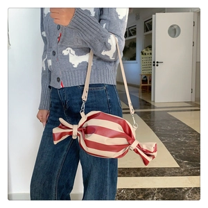 Detail of candy-shaped crossbody bag featuring red and white stripes and silver hardware