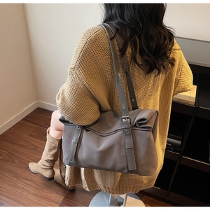 Detail of dark grey suede tote bag with metal eyelet straps worn with knit cardigan