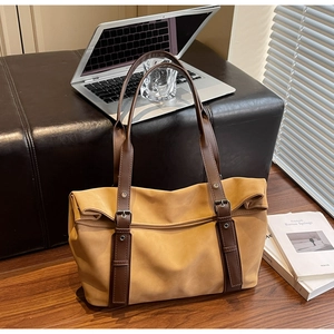 Macro detail of mustard tote bag with dark brown straps, rivets and buckle accents