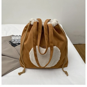 Close-up of brown suede bucket bag with plush white heart and faux shearling trim