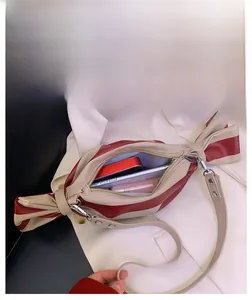 Detail showing the spacious interior of the red-beige striped candy-shaped crossbody bag