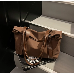 Detail of mocha tote bag with rolled edge design and leather handles on stairs