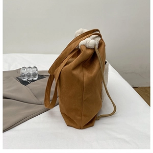 Detail of suede tote with white faux fur trim and drawstring closure in soft light