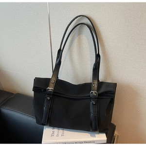 Detail of black large tote bag with leather handles and silver metal buckle accents