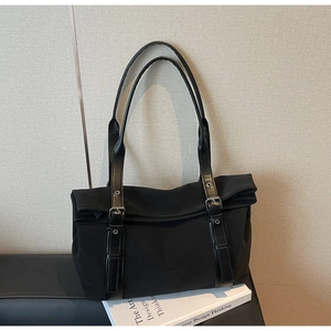 Detail of black nylon tote bag with flap closure and adjustable leather straps