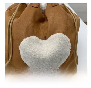 Close-up of brown suede bag showing fuzzy white lamb wool heart patch and soft texture