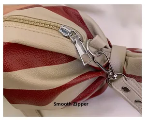 Détail de fermeture éclair argentée lisse et cuir à grain de litchi sur sac à rayures
