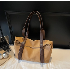 Detail of large khaki tote bag showing adjustable brown straps with metal buckles