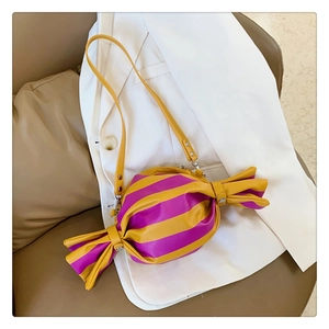 Close-up of candy-shaped shoulder bag with vibrant yellow and purple stripes on white blazer