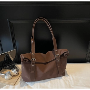 Detail of dark brown tote bag with adjustable straps and silver buckle hardware