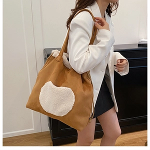 Brown faux suede tote with lamb wool heart patch shown as a crossbody shoulder bag