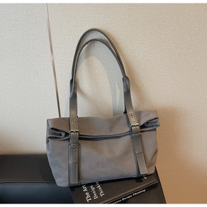 Detail of grey suede tote bag with double handles and decorative buckle straps