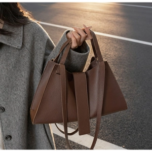 Close-up of brown litchi grain leather handbag with top handle and shoulder strap