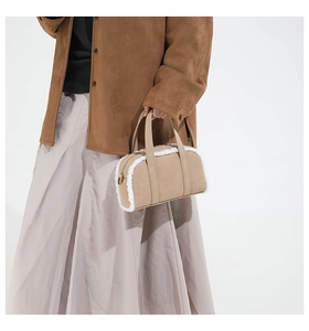 Detail of beige suede bowling bag featuring soft plush shearling trim and top handle strap