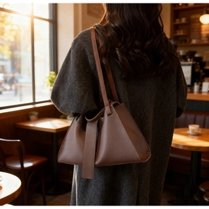 Brown leather tote bag featuring a unique trapezoid design and sleek vertical leather straps