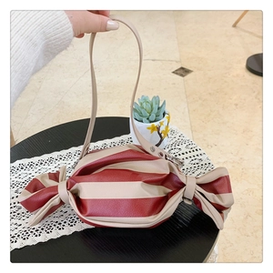 Detail of candy-shaped crossbody bag featuring red and white stripes and side knots
