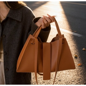 Brown lychee leather tote bag with long handles shown on model in outdoor sunlight