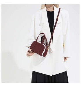Detail of burgundy canvas bowling bag with white faux fur trim and gold metal hardware