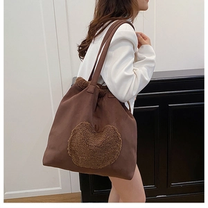 Detailed view of large brown suede bucket bag with plush heart detail and dual handles