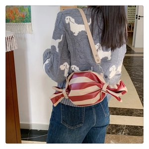 Detail of red and white striped candy shaped crossbody bag worn by a model