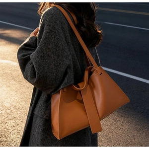 Side view of caramel leather tote bag with pebble texture and minimalist wide strap design