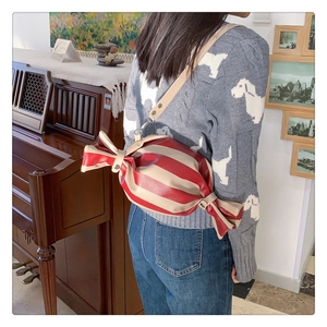 Close-up of candy-shaped crossbody bag with red and beige stripes and silver hooks