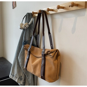 Close-up of a large light brown tote bag hanging with denim jacket and headphones