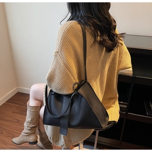 Close-up of black leather tote bag with lychee grain texture and adjustable strap